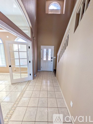 A hallway with a diamond pattern on the floor leading to a white door.