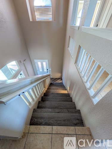 A staircase with a wooden handrail and tiled floor leads up to a bright room.