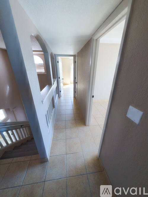 A hallway with a tiled floor and a staircase on the left side.