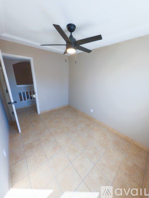 A room with a ceiling fan and tile flooring.
