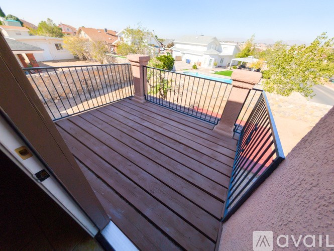 A wooden deck with a metal railing overlooks a residential area.