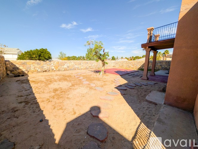 A balcony overlooks a sandy yard.
