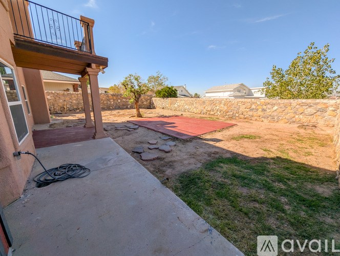 A balcony overlooks a patio with a red tile floor and a stone wall.