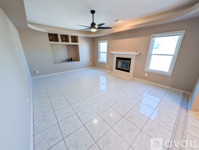 A spacious living room with a fireplace and a ceiling fan.
