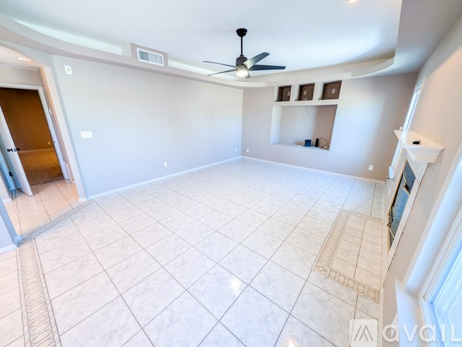 A spacious room with a ceiling fan and tiled flooring.