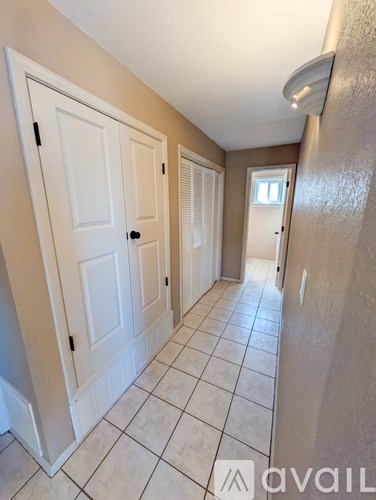 A hallway with white doors and tiled floors.