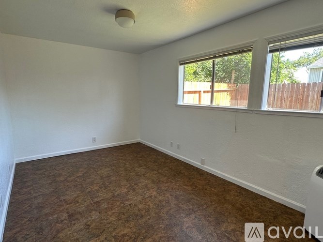 A room with a window and a wooden floor.