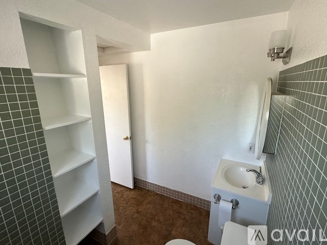A bathroom with a toilet, sink, and shelves.