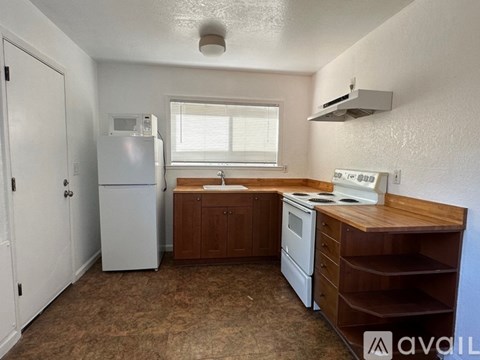 A small kitchen with a white refrigerator, white stove, and brown cabinets.