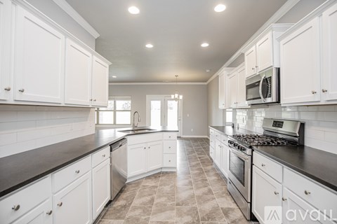 A kitchen with white cabinets and a black countertop.