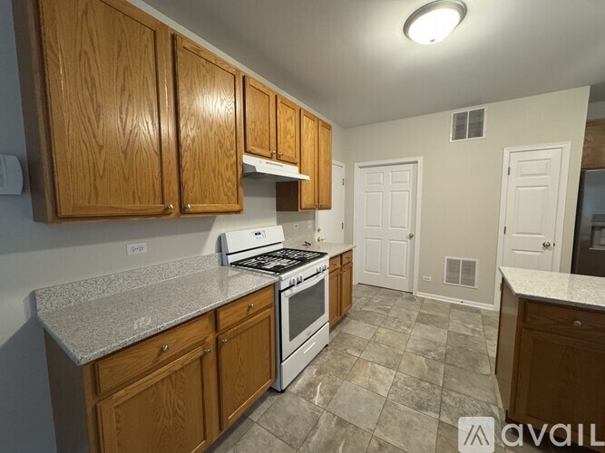 A kitchen with wooden cabinets and a tiled floor.