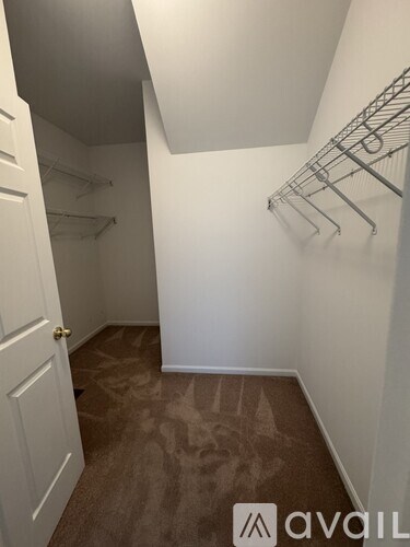 A walk in closet with a white door and shelves.