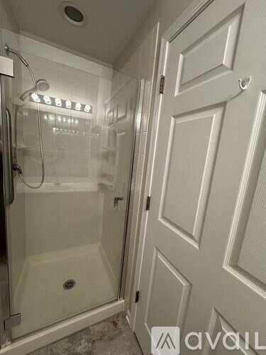 A white bathroom with a glass shower stall and a white door.