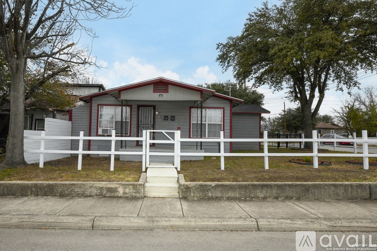 A house with a red roof and white fence is for sale.