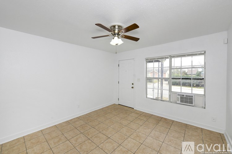 A room with a ceiling fan and a window overlooking a street.
