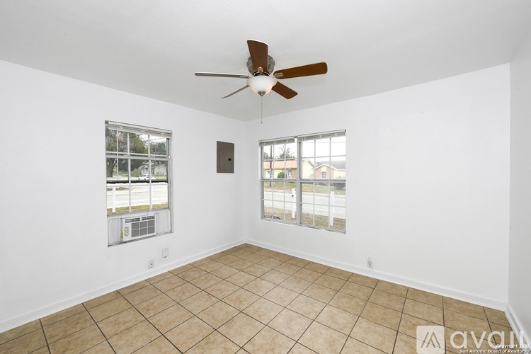 A room with a ceiling fan and two windows.