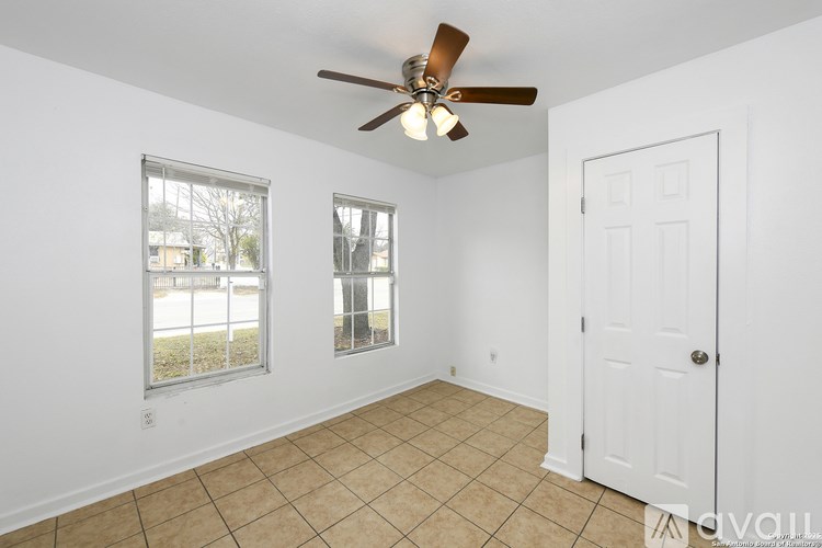 A room with a ceiling fan and two windows.