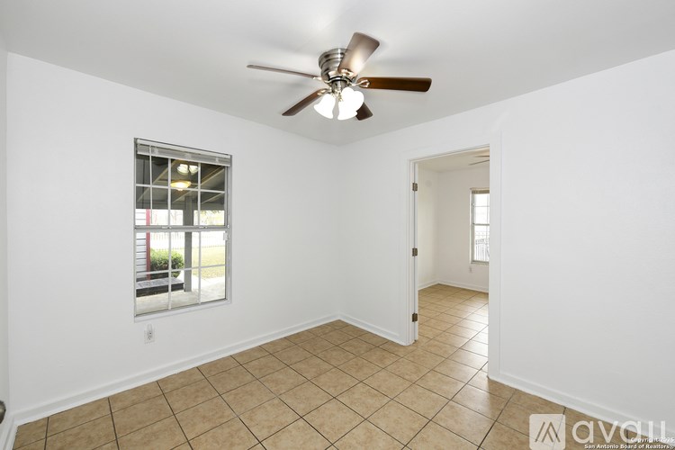 A room with a ceiling fan and a window with a view of a parking lot.
