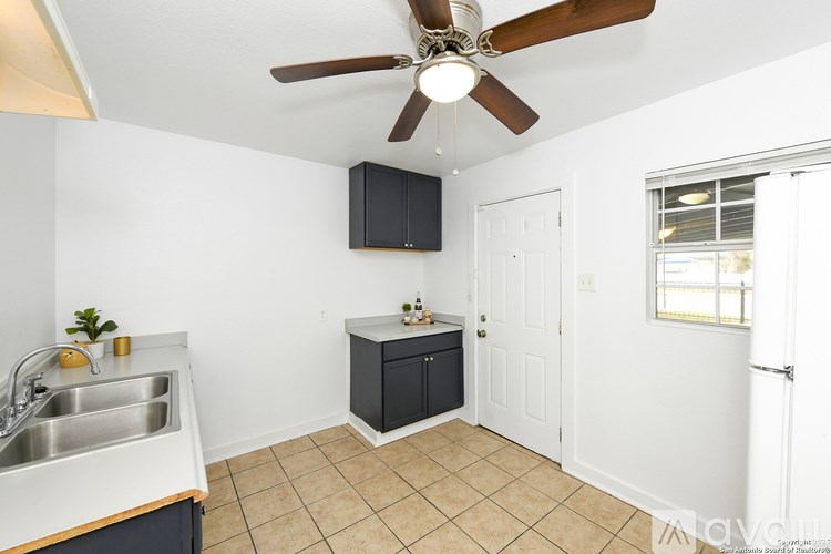 A kitchen with a sink, a ceiling fan, and a window.