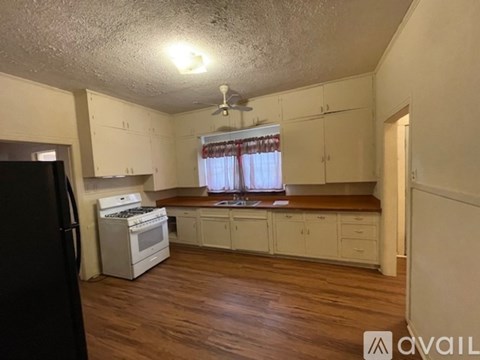A kitchen with white cabinets and a black refrigerator.