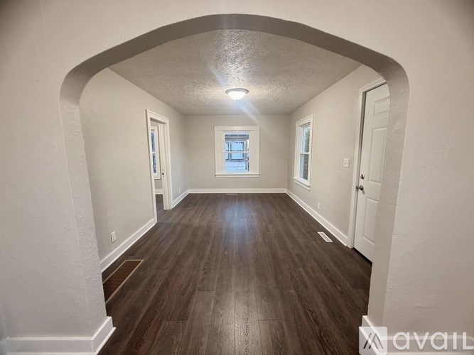 A long hallway with wood floors and white walls.