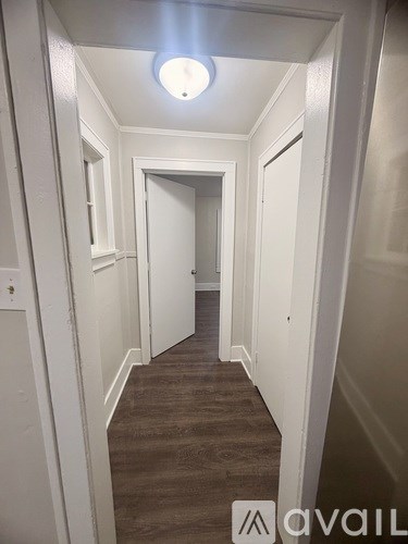 A long hallway with white walls and a light on the ceiling.