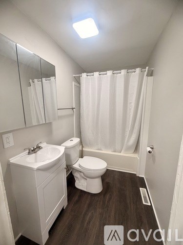 A small, clean, white bathroom with a toilet, sink, and shower curtain.