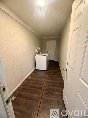 A hallway with a washing machine in the doorway.