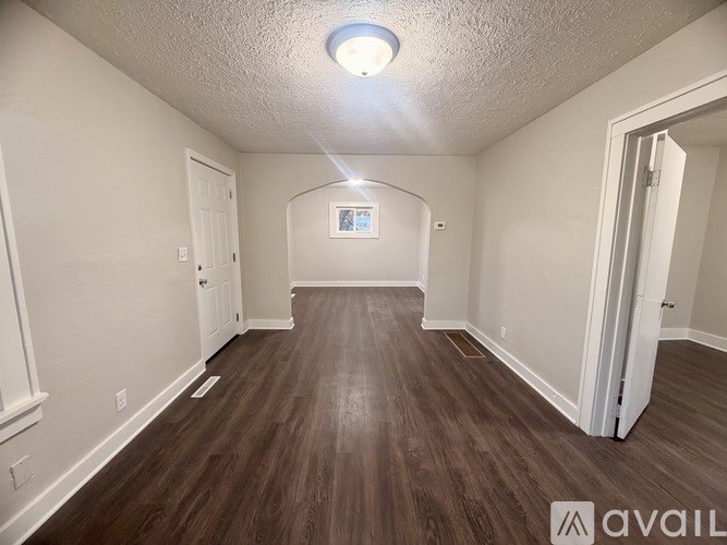 A spacious room with wood flooring and white walls.