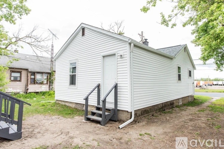 A small white house with a porch and a black railing.