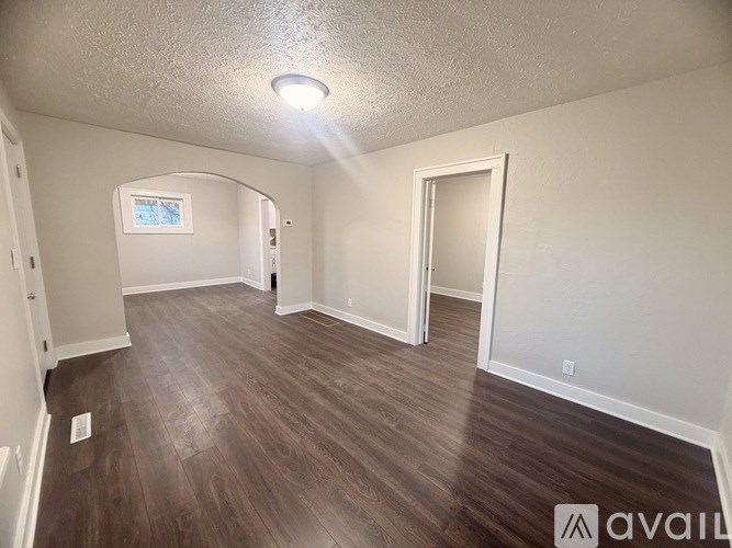 A room with wooden flooring and a window in the corner.
