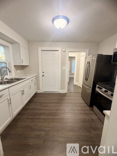 A kitchen with white cabinets and a wooden floor.