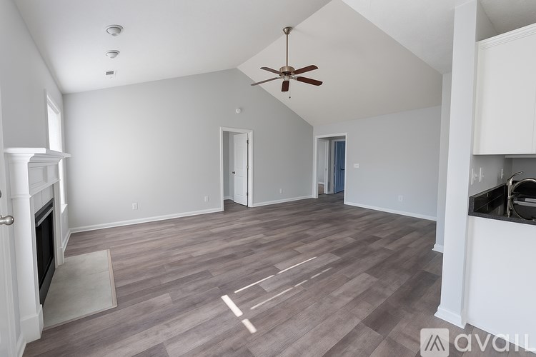A spacious living room with a fireplace and a ceiling fan.