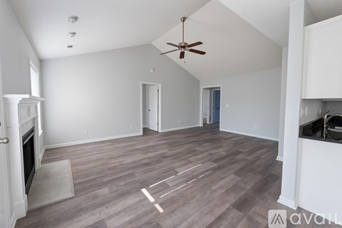 A spacious living room with a fireplace and a ceiling fan.
