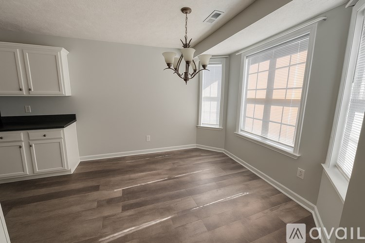 A room with wooden flooring and a chandelier hanging from the ceiling.