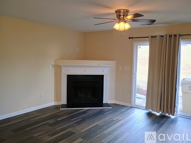 A living room with a fireplace and a ceiling fan.