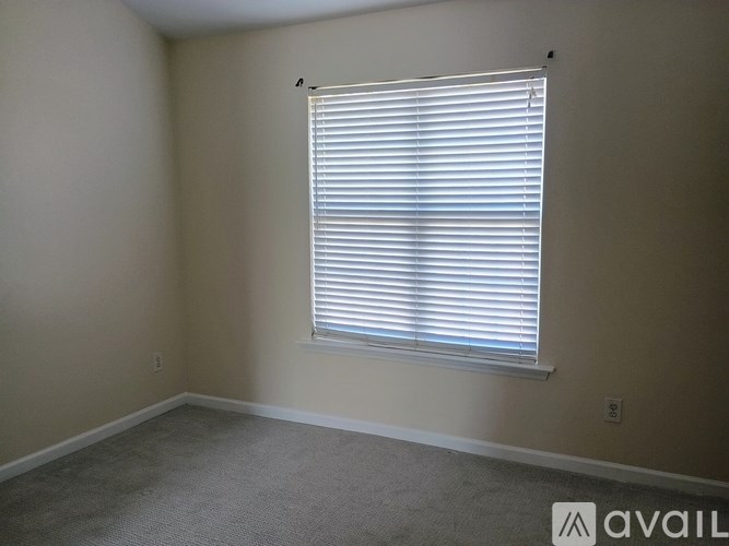 A room with a window covered in white blinds.