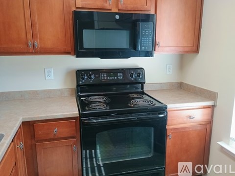 A black stove and microwave in a kitchen with wooden cabinets.