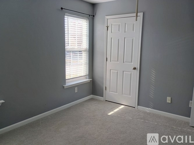 A room with a white door and a window with blinds.