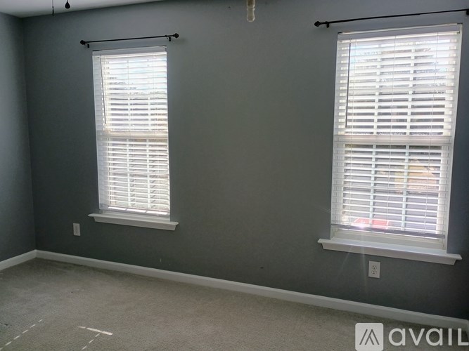 A room with two windows covered in white blinds.