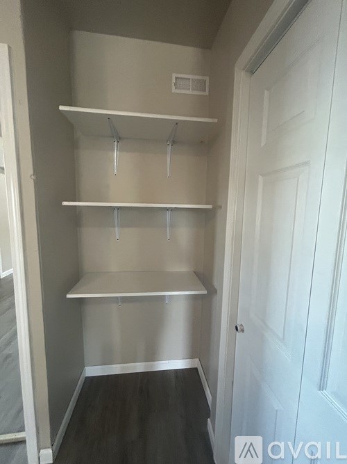 A white door is on the right of a white shelving unit.