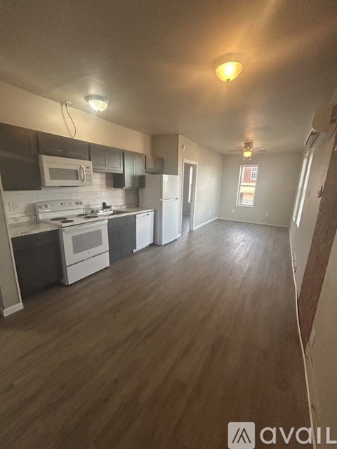 A kitchen with white appliances and black cabinets.