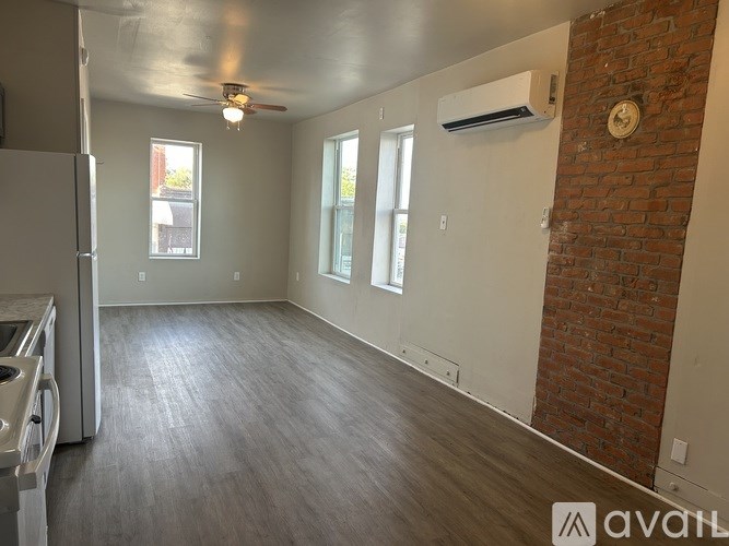 A spacious room with a brick wall and wood flooring.