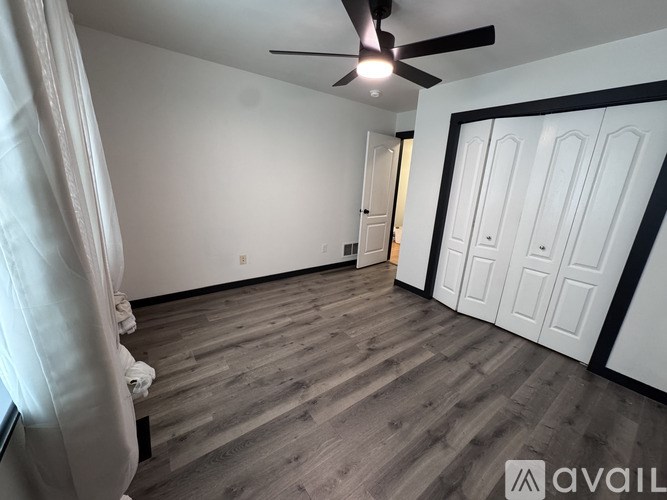 A room with a ceiling fan and wooden flooring.