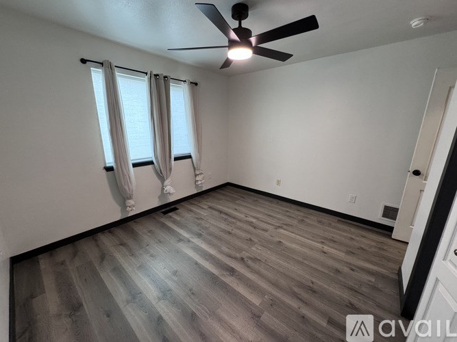 A room with a ceiling fan and wooden flooring.