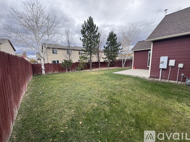 A backyard with a red fence and a green lawn.