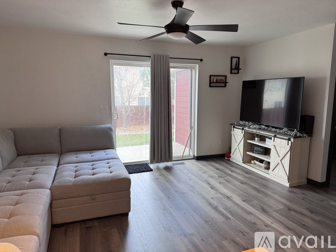 A living room with a grey sofa, a television, and a sliding glass door.