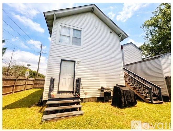 A house with a white siding and a grey roof with a small front porch.