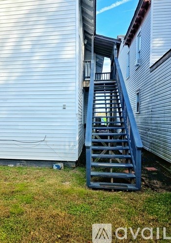 A blue staircase is in front of a silver siding house.