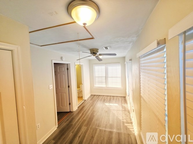 A long hallway with a light on the ceiling and a fan on the wall.